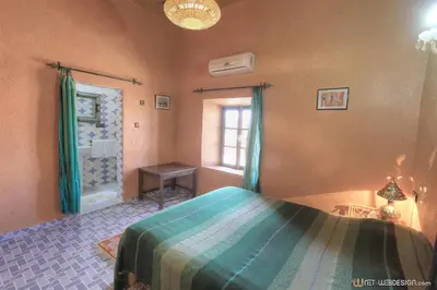 a bedroom with a bed and a window and a shower at La Porte du Dades in Boumalne