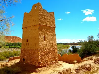 an old brick building sitting on top of a hill at gîte les jardins in Goulmima