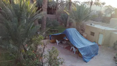 a patio with a blue tarp over a table and chairs at gîte les jardins in Goulmima