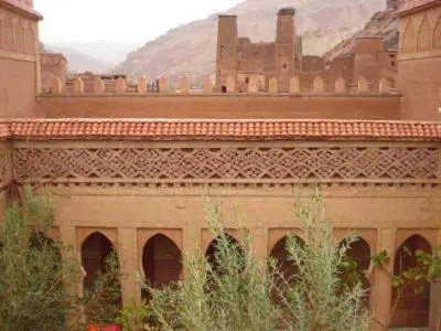 a building with arches and a mountain in the background at Riad Berbère Boutaghrar in Bou Tharar