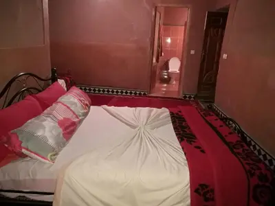 a bed with a red and white blanket on it at Riad Berbère Boutaghrar in Bou Tharar