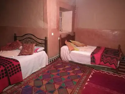 a room with two beds and a mirror at Riad Berbère Boutaghrar in Bou Tharar