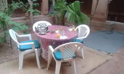 a table with four chairs and a table with a purple at Riad Berbère Boutaghrar in Bou Tharar