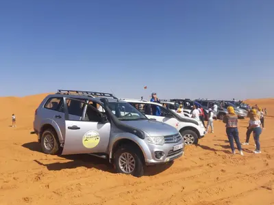 a group of cars parked in the desert at Appartement belkacem in Merzouga