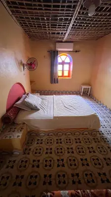 a bedroom with two beds and a window at Appartement belkacem in Merzouga