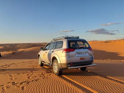 a suv driving through the sand in the desert at Appartement belkacem in Merzouga