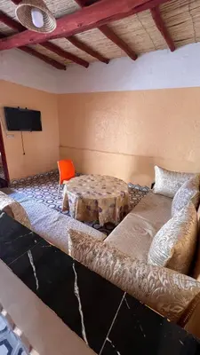 a room with a couch and a table and a tv at Appartement belkacem in Merzouga