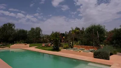 a swimming pool in a yard with a landscaping at Asnouss in Marrakech