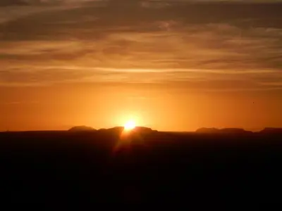 a sunset over the mountains with the sun in the sky at Maison d'hôtes Dar El Nath in Ouarzazate