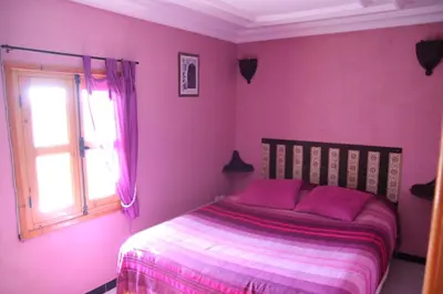 a bedroom with pink walls and a bed with a window at Maison d'hôtes Dar El Nath in Ouarzazate