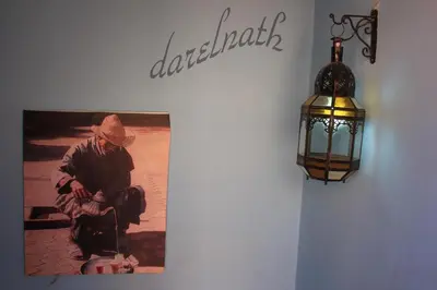 a picture of a man sitting on a wall next to a lamp at Maison d'hôtes Dar El Nath in Ouarzazate