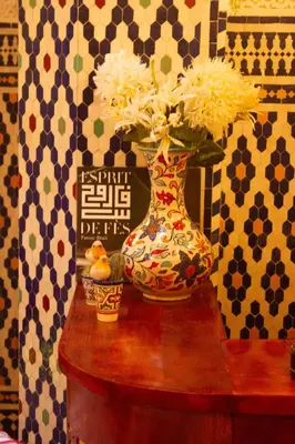 a vase with flowers in it sitting on a table at Dar Lantana in Fès