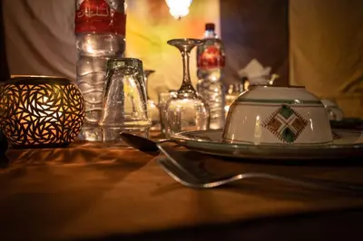 a table with a plate and glasses on a table at Mhamid Sahara Luxury Camp - Chez Naji in Mhamid