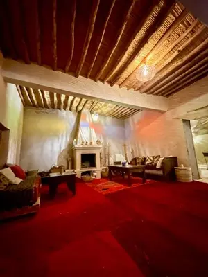 a living room with a fireplace and a red carpet at Mhamid Sahara Luxury Camp - Chez Naji in Mhamid
