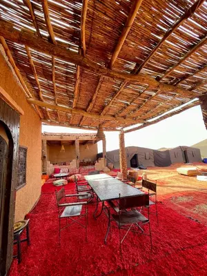 a room with a table and chairs on a red rug at Mhamid Sahara Luxury Camp - Chez Naji in Mhamid