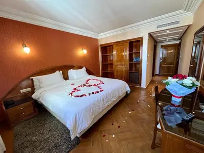 a bedroom with a bed with red flowers on it at Hotel Malta in Meknès