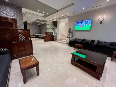 a living room with a couch and a tv on a wall at Hotel Malta in Meknès