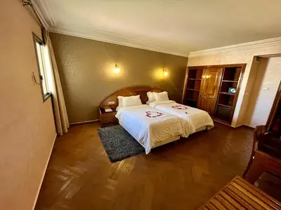 a bedroom with a large bed with a white bedspread at Hotel Malta in Meknès