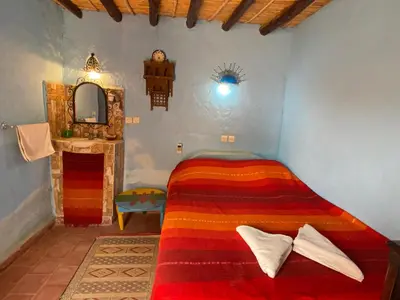 a bedroom with a bed and a mirror at Auberge Kasbah Des Dunes in Merzouga