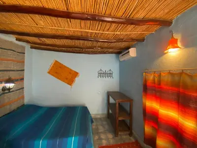 a bedroom with a blue bed and a wooden ceiling at Auberge Kasbah Des Dunes in Merzouga