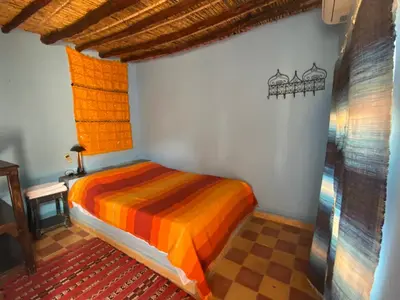 a bedroom with a colorful bed in a room at Auberge Kasbah Des Dunes in Merzouga