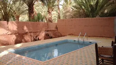 a swimming pool in a yard with palm trees at Dar Nakhla Zagora Guest House Restaurant & Desert Excursions in Zagora