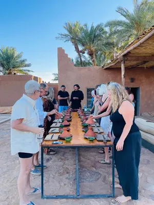 a group of people standing around a table with food on it at Kasbah Aitisfoul in Tagounite