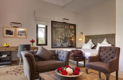 a hotel room with a bed and two chairs and a table at Palais de l'O - Maison d'hôtes in Marrakech