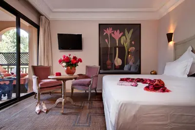 a hotel room with a bed and a table with flowers on it at Palais de l'O - Maison d'hôtes in Marrakech