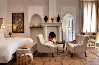 a bedroom with a bed and two chairs and a fireplace at Palais de l'O - Maison d'hôtes in Marrakech