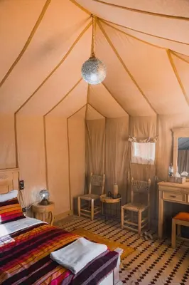 a bedroom with a bed and two chairs in a tent at Royal Luxury Camp in Merzouga