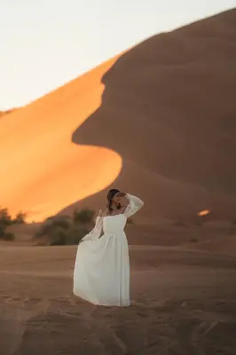 a woman in a white dress standing in the desert at Royal Luxury Camp in Merzouga