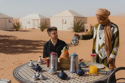 a woman standing next to a table in the desert at Royal Luxury Camp in Merzouga