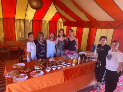 a group of women standing around a table in a tent at Sahara Happy Camp in Merzouga