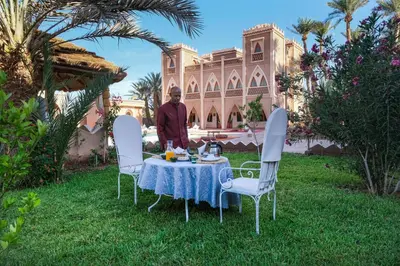 a man standing in front of a table in a yard at Sbai Palace in Mhamid