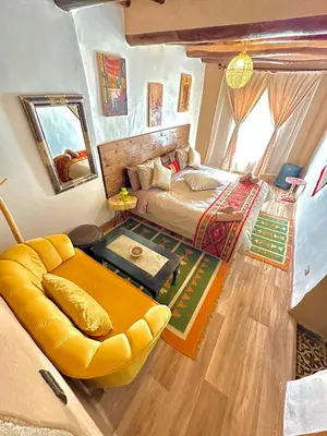 a bedroom with a bed and a large yellow couch at Kasbah El Hajja in Aït Ben Haddou