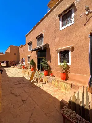 a brick building with potted plants in front of it at Kasbah El Hajja in Aït Ben Haddou