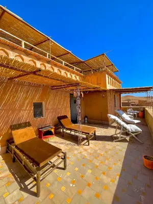 a patio with a building with a grill and tables at Kasbah El Hajja in Aït Ben Haddou