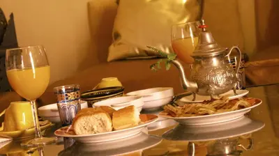 a table topped with plates of food and glasses of wine at Riad Sephora in Tinerhir