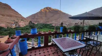 a balcony with blue vases and a table and a mountain at Riad Sephora in Tinerhir