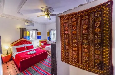 a bedroom with a red bed and a rug at Riad Sephora in Tinerhir