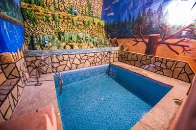 a bathroom with a swimming pool with a painting on the wall at Riad Sephora in Tinerhir