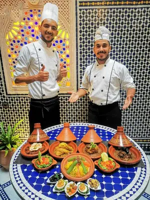 two chefs standing in front of a table of food at Riad Dar El Ouedghiri in Fès