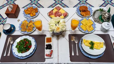 a table with plates of food and glasses of orange juice at Riad Dar El Ouedghiri in Fès