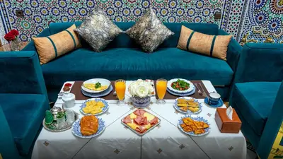 a table with plates of food on a blue couch at Riad Dar El Ouedghiri in Fès