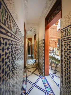 a hallway with a mirror and a wall with tiles at Dar Dalila Fes in Fès