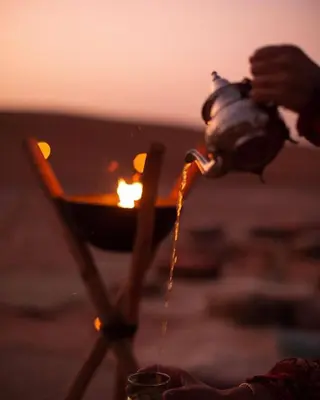 a person is pouring liquid from a fire hydrant at Sahara Desert Experience camp in Merzouga