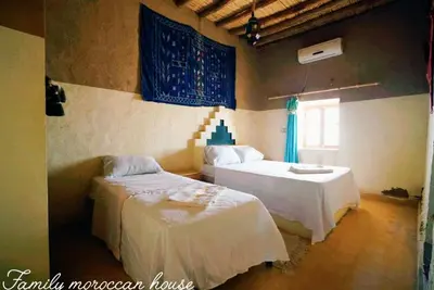 a bedroom with two beds and a window at Family Moroccan House in Merzouga