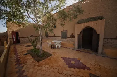 a patio with a table and chairs and a tree at Family Moroccan House in Merzouga