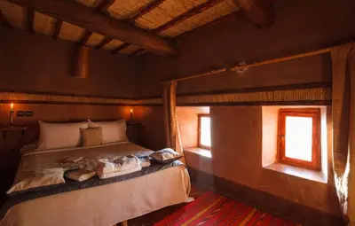 a bedroom with a bed in a room with windows at Kasbah Tebi in Aït Ben Haddou